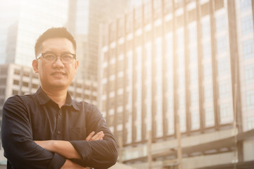 Confident male business executive  with arms crossed standing in front of office building