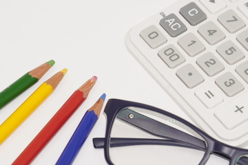 黒縁メガネと色鉛筆と電卓