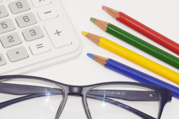 黒縁メガネと色鉛筆・電卓