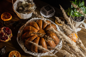 Traditional country style italian Christmas cake wrapped with lace with chocolate, fruits and coffee wooden background.