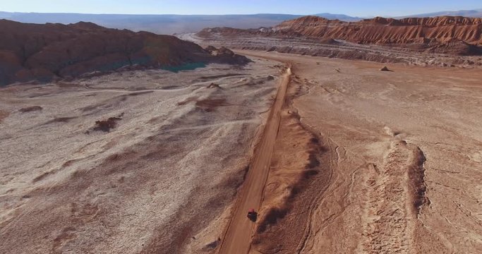 Moon Valley aerial view. Two cars move towards each other on a deserted road in Atacama Desert near San Pedro de Atacama. Lifeless eroded soil everywhere around. Chile. 4K.
