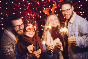 Group of happy friends celebrating New Year with sparklers. New year party.