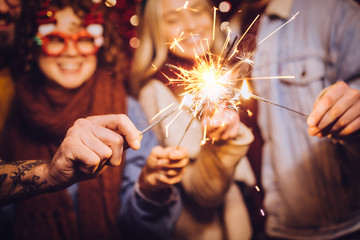 Close view of sparklers. Group of happy friends celebrating New Year with sparklers. New year party.
