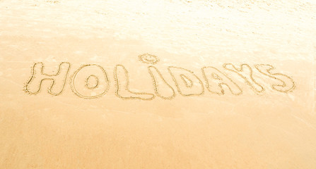 Odręczny napis holidays - wakacje na piasku nad morzem