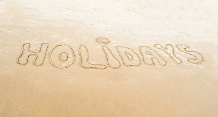 Fototapeta na wymiar Odręczny napis holidays - wakacje na piasku nad morzem