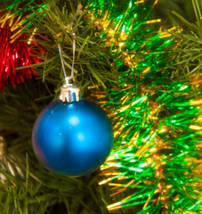 Christmas holiday background. Baubles hanging from a decorated on tree with bokeh and snow, copy space.