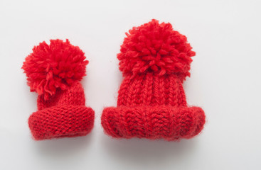 Red knitted wool beanie hat on white table top view.