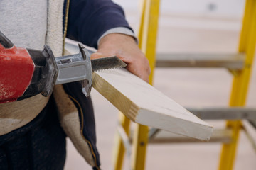 Closeup hand of woodworker with professional cutting tool jigsaw, cut wooden tabletop, sawing plank