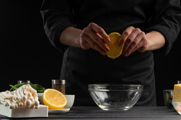 Cooking sauce or salad dressing. With ingredients. On a black background. The chef cooks a lemon, getting juice.