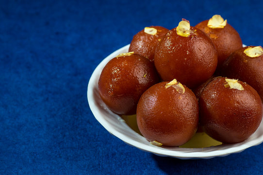 Gulab Jamun, Indian dessert with dry friut in white bowl with napkin