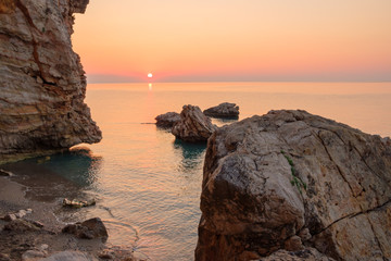 dawn on the sea the sun and big boulders in the water