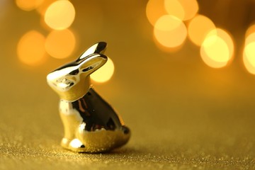 Easter bunny. Golden easter metallic bunny on golden glitter background with shining bokeh.Easter...