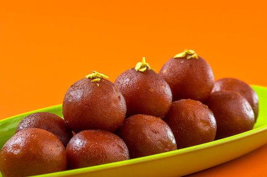 Indian Dessert Gulab Jamun in plate on orange background