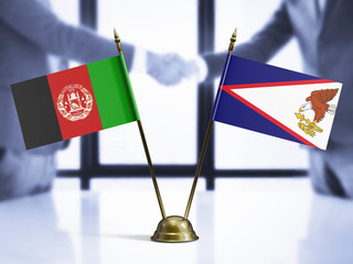 American Samoa and Afghanistan mini table flags on white wooden desk. Diplomatic background with...