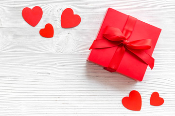 Gift to a sweetheart on Valentine's Day. Red present box near hearts on white wooden background...