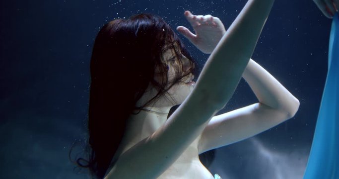 sexual mermaid is floating underwater in ocean, playing with light blue fabric