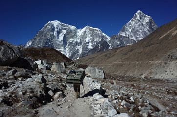 Fototapeta na wymiar Everest trek, Porters are carrying extremely big load, View of Tabuche Peak, Cholatse and Arakam Tse. Sagarmatha national park, Solukhumbu, Nepal