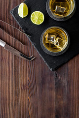 Bar background with whiskey and ice on dark wooden desk top-down frame copy space