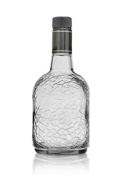 Empty bottle for rum or brandy with a pattern, closed with a plastic lid. On a white background with reflection.
