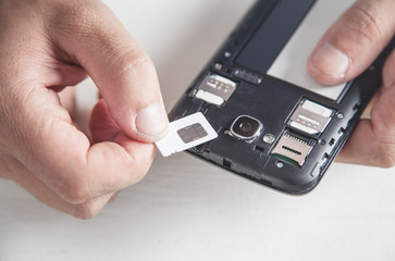 Man holding Sim Card with smartphone.