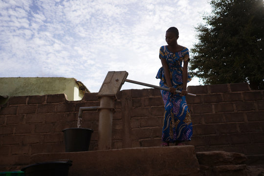 African Teenage Girl Pumping Water At The Borehole
