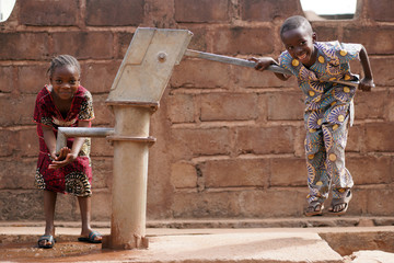 Happy Little African Boy Pumping Water For His Sister