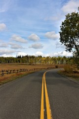 Typical road through western canada. Through rural lonesome fields and countryside with wooden fences while indian summer.