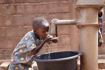 Small African Boy Sipping Clean Fresh Water From A Modern Pumping Station