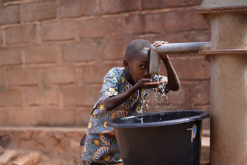Little African Boy At The Community Borehole Quenching His Thirst  - obrazy, fototapety, plakaty