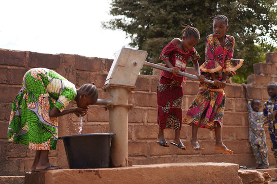 Young Girls Pumping Water At A Public Borehole in West Africa
