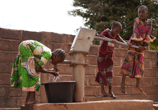 Three African Girls Filling Up Water Buckets At A Public Borhole Pump