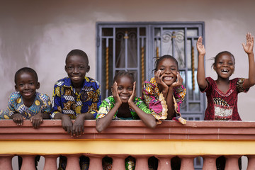 Five African Children Greeting Bypassers From A Colonial House Balcony - obrazy, fototapety, plakaty