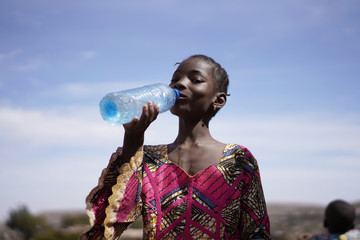 Skinny Young African Girl Drinking Water From A Plastic Bottle