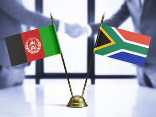 South Africa and Afghanistan mini table flags on white wooden desk. Diplomatic background with men shaking hands, international relations and agreements.