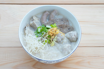 Congee with minced pork, braised pork filling, boiled pork liver, fried garlics minced pork in white bowl. Asian breakfast.