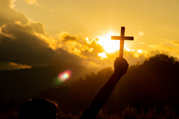 Silhouette of woman praying with cross in nature sunrise background, Crucifix, Symbol of Faith....