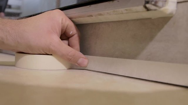 locked off close up of man laying masking tape on floor