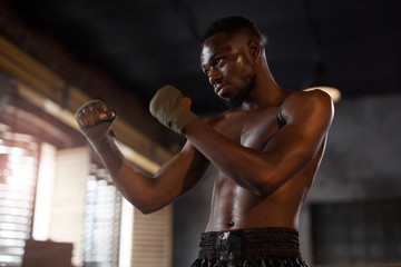 Muscular African boxer has a sports training he standing and fighting in gym
