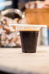 Close up of coffee drink in plastic take out cup with a straw on top 