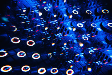 DJ mixer in a nightclub with a background of glowing lights from buttons