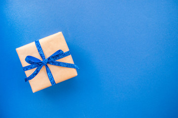 Flat lay of giftbox tied with classic blue color ribbon on blue background. 2020 color trend.