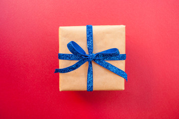 Flat lay of giftbox tied with classic blue color ribbon on blue background. 2020 color trend.