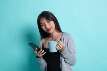 Fototapeta premium Young Asian woman with mobile phone and coffee cup.