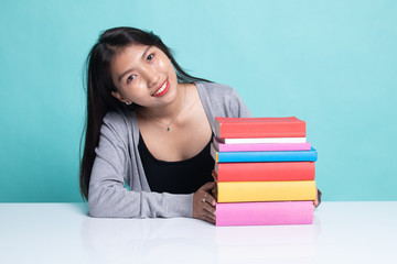 Happy young Asian woman read a book with books on table.