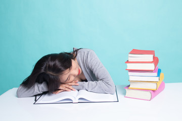 Exhausted Young Asian woman sleep with books on table.