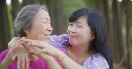 Cheerful mature woman embracing senior mother