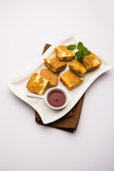Amritsari Paneer Tikka made using cottage cheese cubes dipped in a batter made with besan, chat masala and spices and shallow fried in pan, served with ketchup
