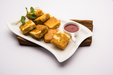 Amritsari Paneer Tikka made using cottage cheese cubes dipped in a batter made with besan, chat masala and spices and shallow fried in pan, served with ketchup