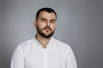 Obraz premium calm handsome bearded man poses in studio on gray background