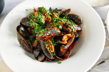 cooked mussels with spices and herbs, laid out in a white plate